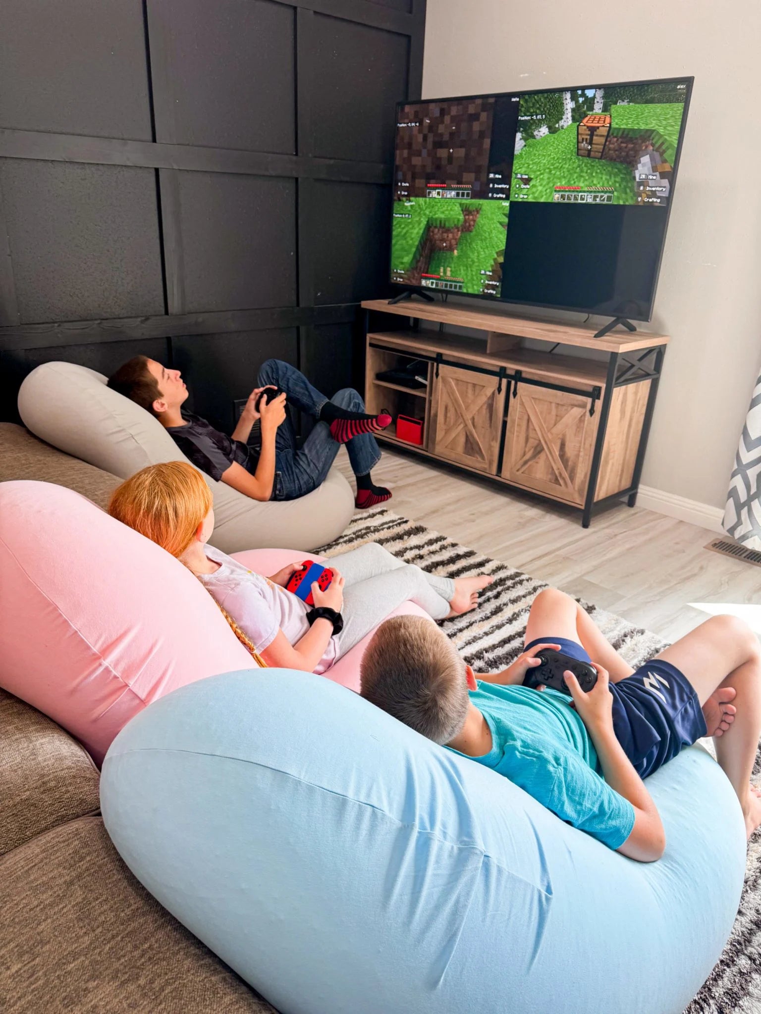 Two people playing video games on a large TV screen in a living room.