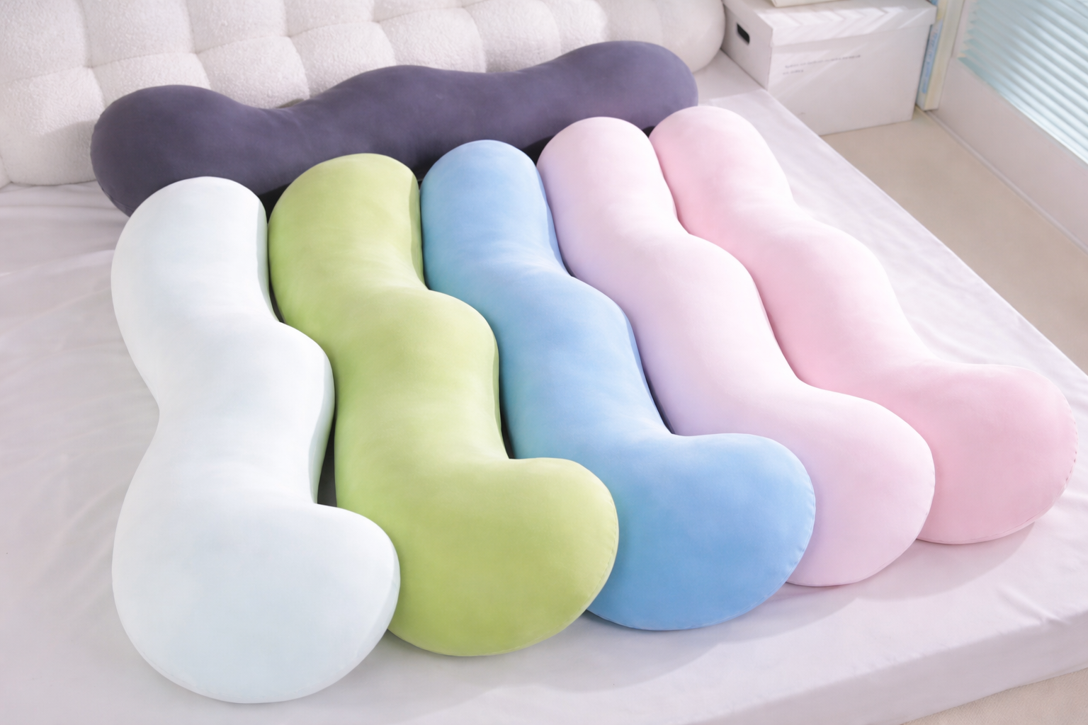 Set of colorful U-shaped pillows on a bed