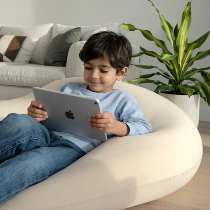 Child sitting on a bean bag chair using an Apple tablet in a living room.