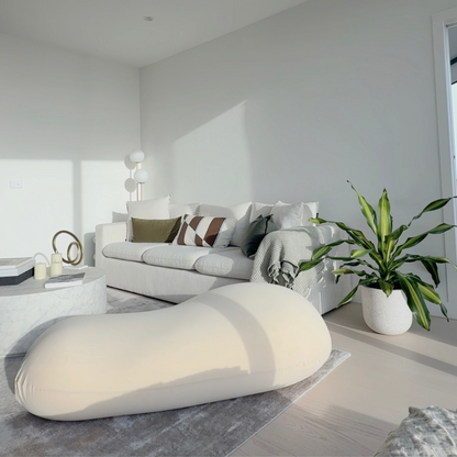 Modern living room with a white sofa, bean bag, and potted plant.