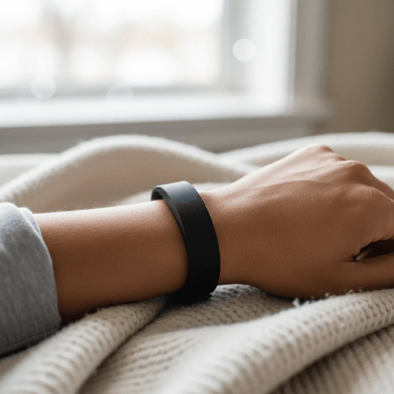 Person wearing a black smartwatch on a blurred indoor background